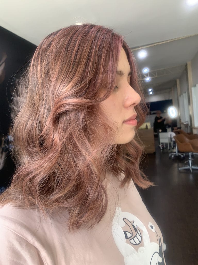 "Experience a playful and feminine look with this pretty pink hair color, created using soft highlights to add dimension and depth. Located in the trendy St Kilda area of Melbourne, this hairstyle is finished with a soft, bouncy blow dry that perfectly complements the playful pink tones."