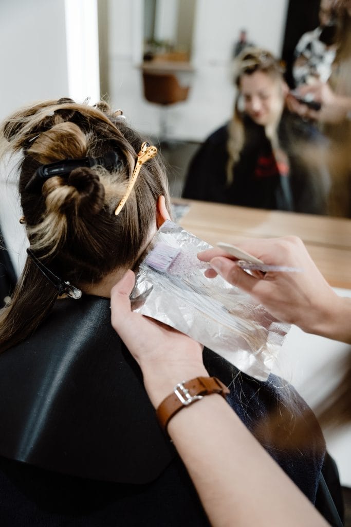 Experience the art of hair colouring with this stunning image of a professional hairdresser expertly applying highlights to a client's hair. Using a highlighting technique, this skilled stylist is able to create a natural-looking finish that perfectly complements the client's skin tone and facial features. Whether you're looking to enhance your natural beauty or try something new, this highlighting service is sure to leave you feeling confident and beautiful.